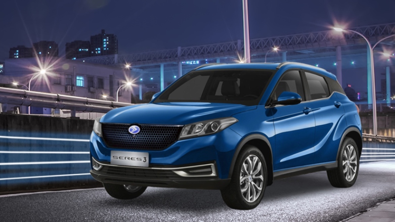 Vehículo eléctrico Seres 3 en carretera con efectos futuristas con edificios de fondo.